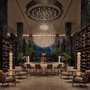 Bar with palms, seating and a chandelier as a centerpoint